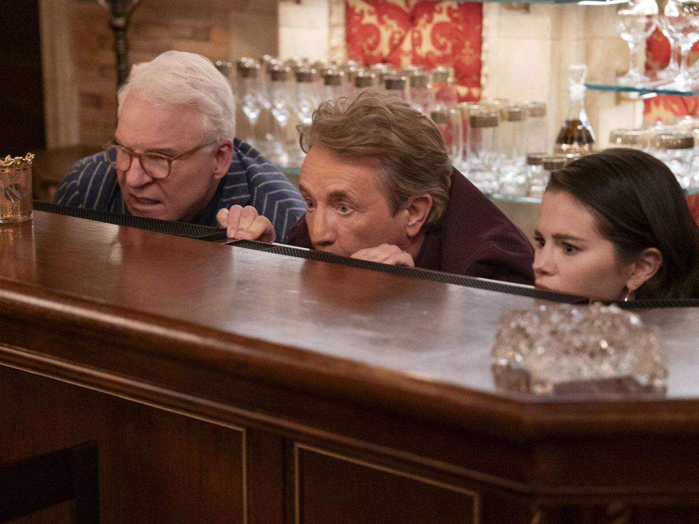 Charles, Oliver, and Mabel hide behind the Velvet Room's bar