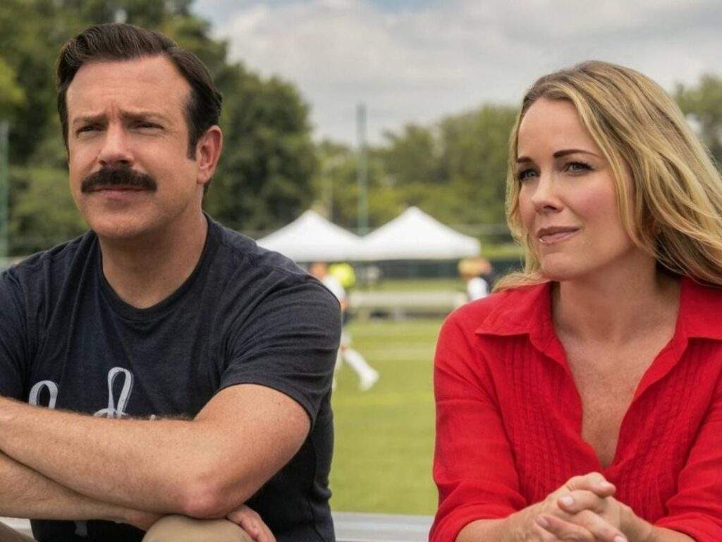 Ted (Jason Sudeikis) and his ex-wife Michelle (Andrea Anders) are sitting beside each other as they watch their son play football/soccer.