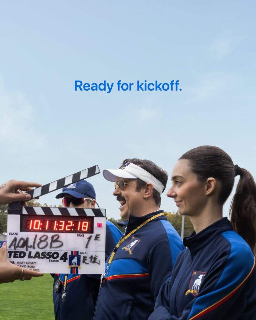 The Ted Lasso season 4 official poster features cast members (L-R) Brendan Hunt, Jason Sudeikis, and newcomer Tanya Reynolds looking on as coaches of a football team. The tagline "Ready for kickoff." is shown above them. Someone (whose face is not shown) is holding a clapperboard, which says "Ted Lasso 4", in front of them.