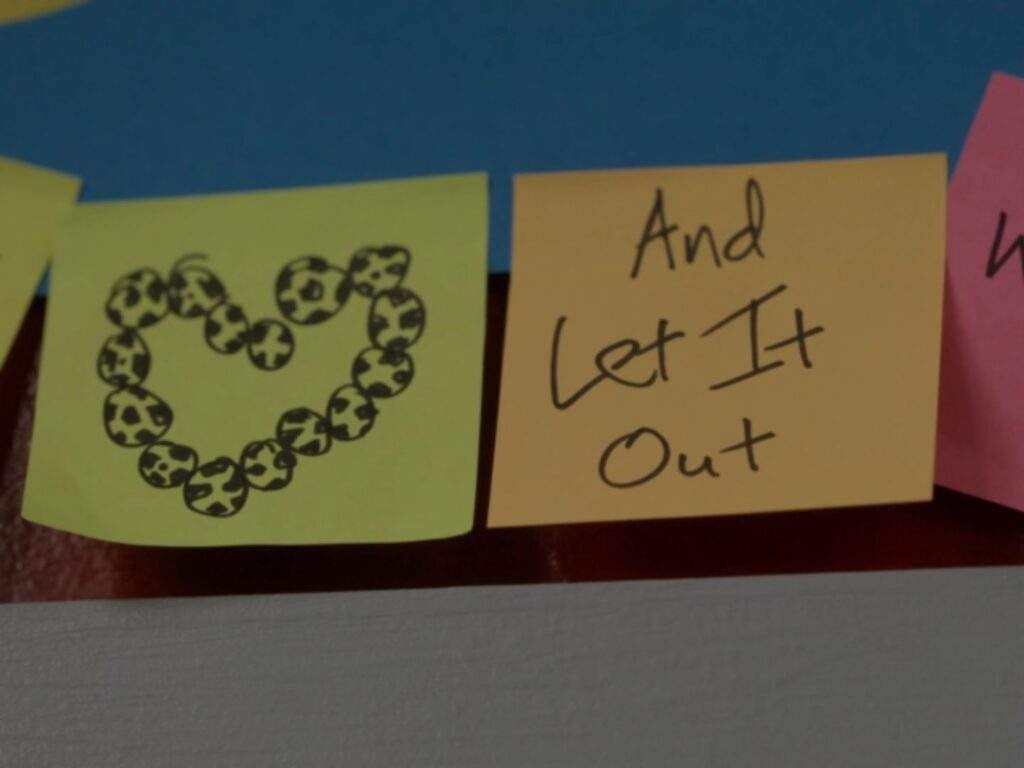 Close-up of the AFC Richmond "Believe" sign covered with colorful sticky notes. One note shows a heart made of footballs, while another reads, "And Let It Out," completing the message, "Believe... And Let It Out."